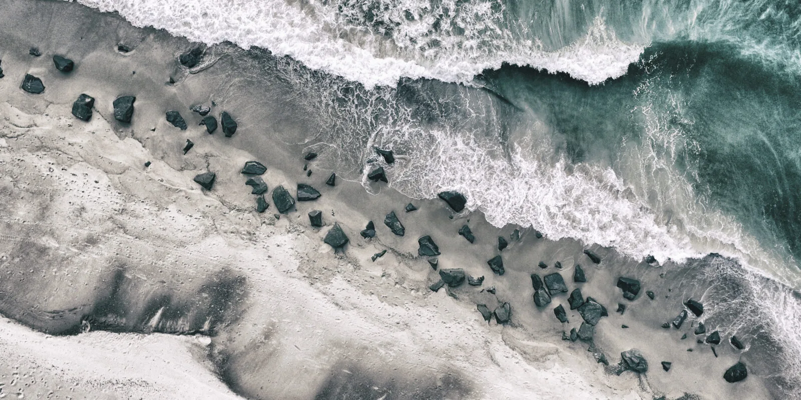 foto dall'alto di un'onda che si infrange sulla spiaggia